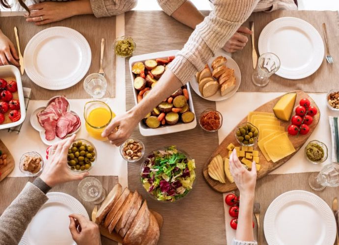 Overhead view of a diverse cheese platter setup for a delicious meal, featuring fresh produce and juices on a table.